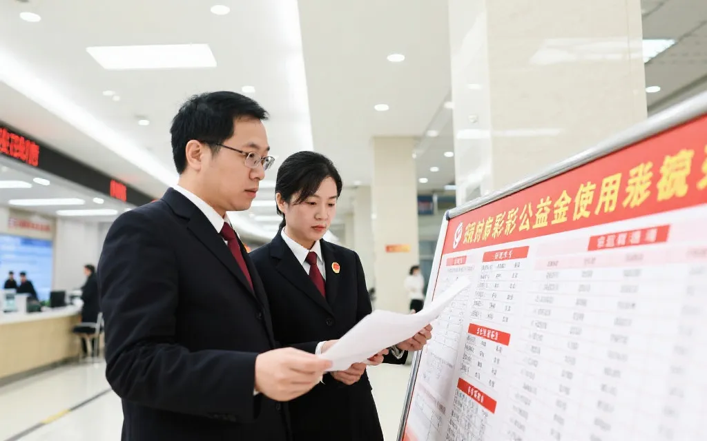 政府工作人员审阅彩票公益金使用公开目录,背景为现代化政务大厅